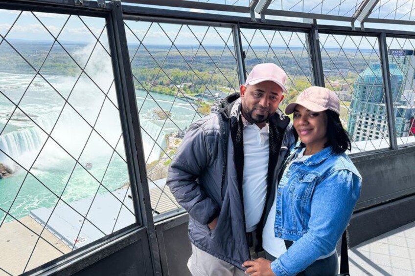 A couple standing on a glass bridge with a view of a waterfall. 5