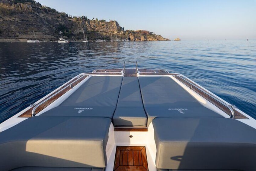 A boat's deck with seating and a view of calm water and distant rocky coastline. 5