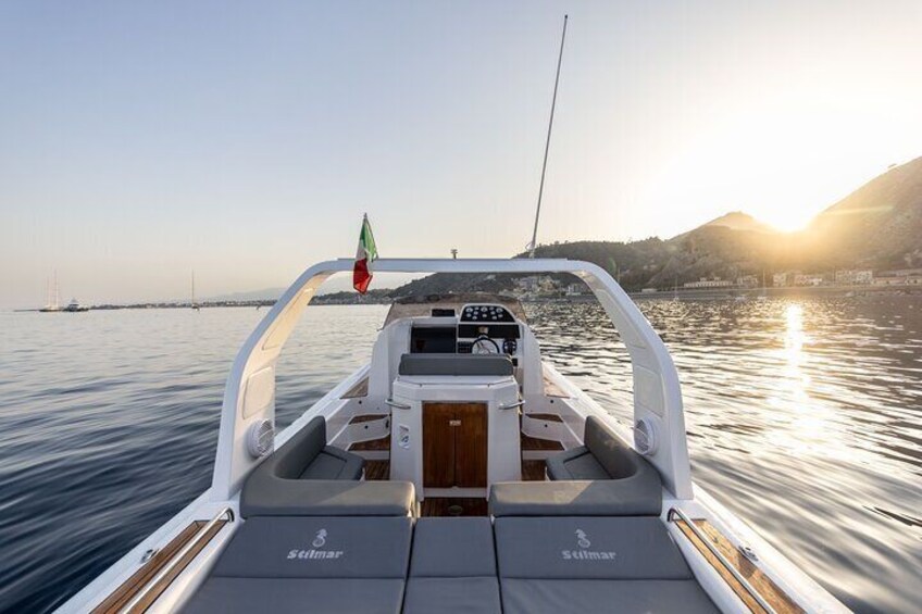 A boat with a steering wheel, a flag, and a logo on the back. 4