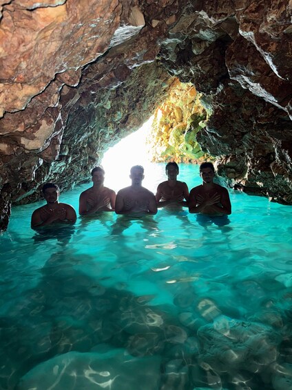A group of people in a natural cave with clear water. 3