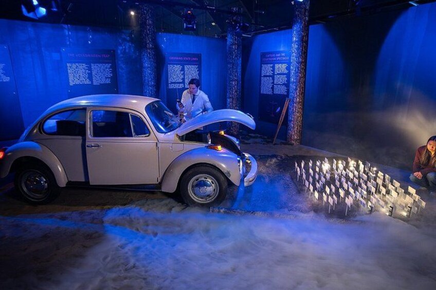 A vintage car in a museum exhibit with informational displays in the background. 4
