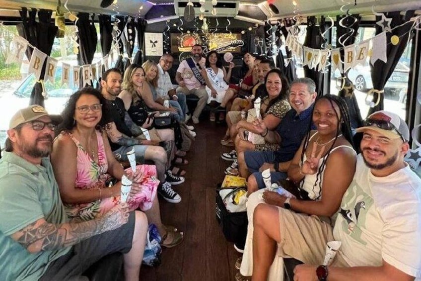 A group of people seated inside a bus, decorated with banners and lights. 1