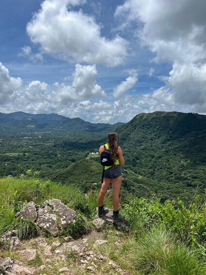 A person standing on a rocky outcrop overlooking a mountainous landscape. 1