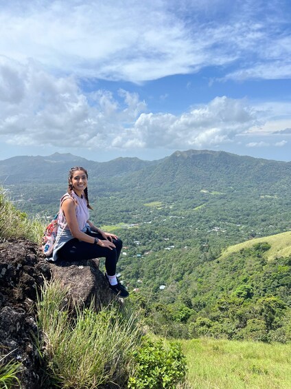 A person sitting on a rock with a mountainous landscape in the background. 4