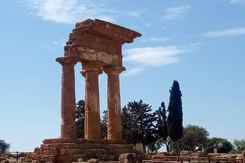 Ancient ruins with columns, a clear sky, and a tall tree. 5
