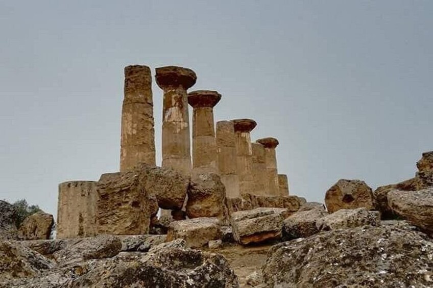 Ancient stone columns with a weathered texture, surrounded by large rocks and a clear sky. 1