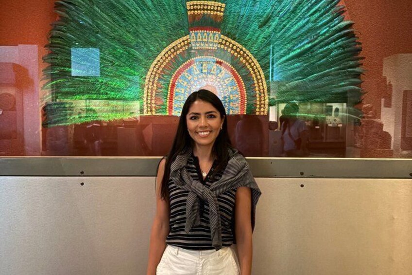 A person standing in front of a colorful mural with a circular design and a peacock feather pattern. 1
