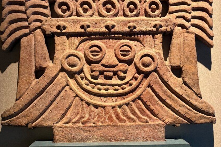 A stone carving with a large face, intricate patterns, and a curved structure. 3