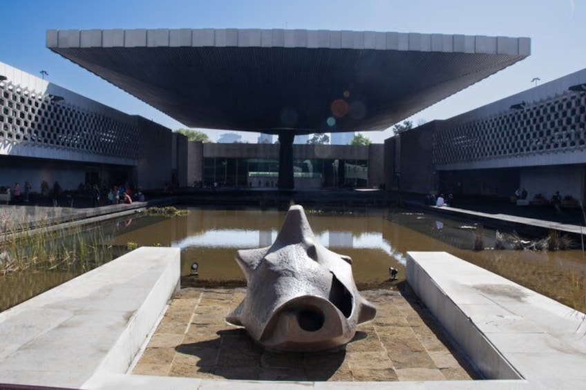 A modern building with a unique roof structure and a central water feature. 4