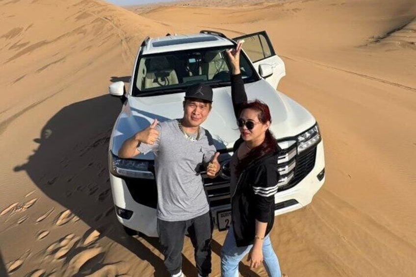 Two people standing in front of a white SUV in a desert landscape. 5