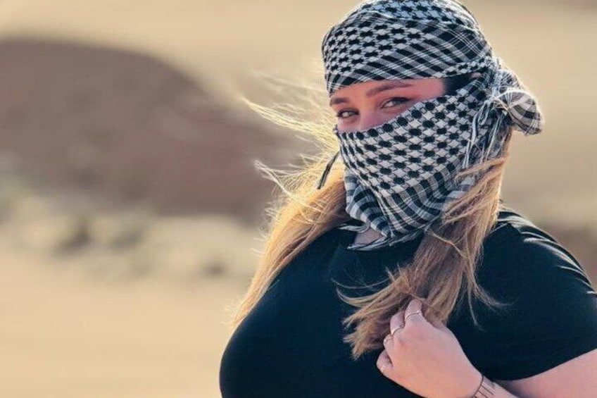 A person in a desert environment with a checkered headscarf and a black shirt. 2