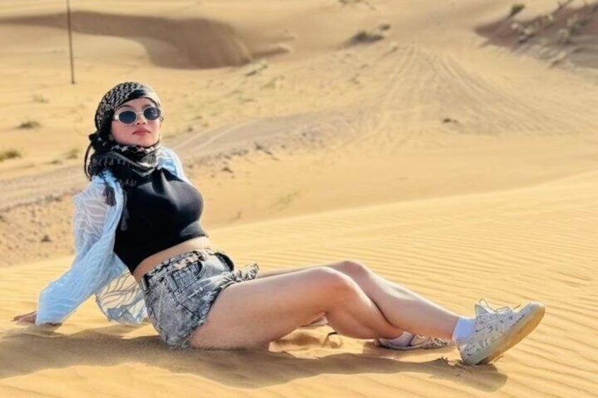 A person sitting on a sand dune in a desert landscape. 4