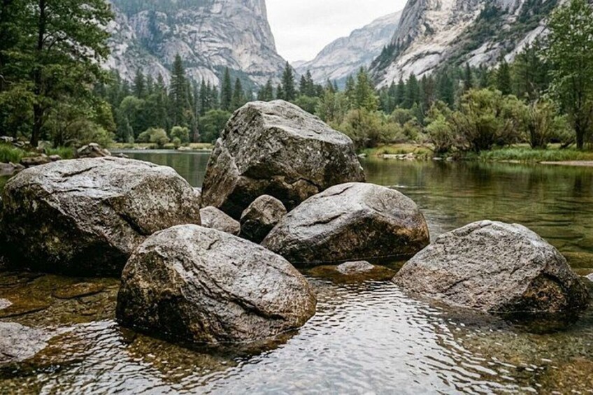 A river with large rocks in the foreground and mountains in the background. 1