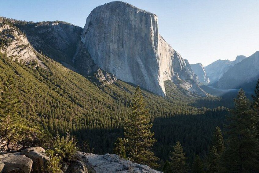 A mountain landscape with a prominent rock formation, dense forest, and a valley. 5