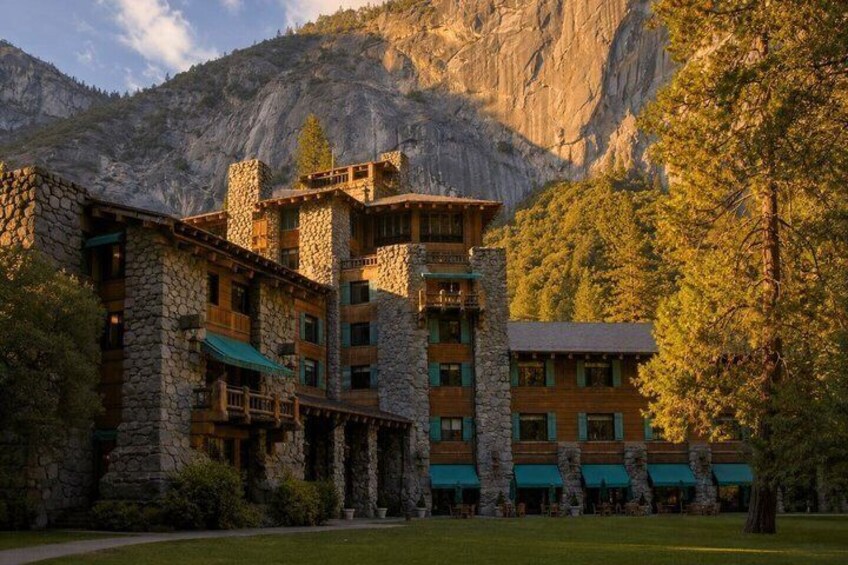 A stone building with multiple balconies, surrounded by trees and mountains. 3