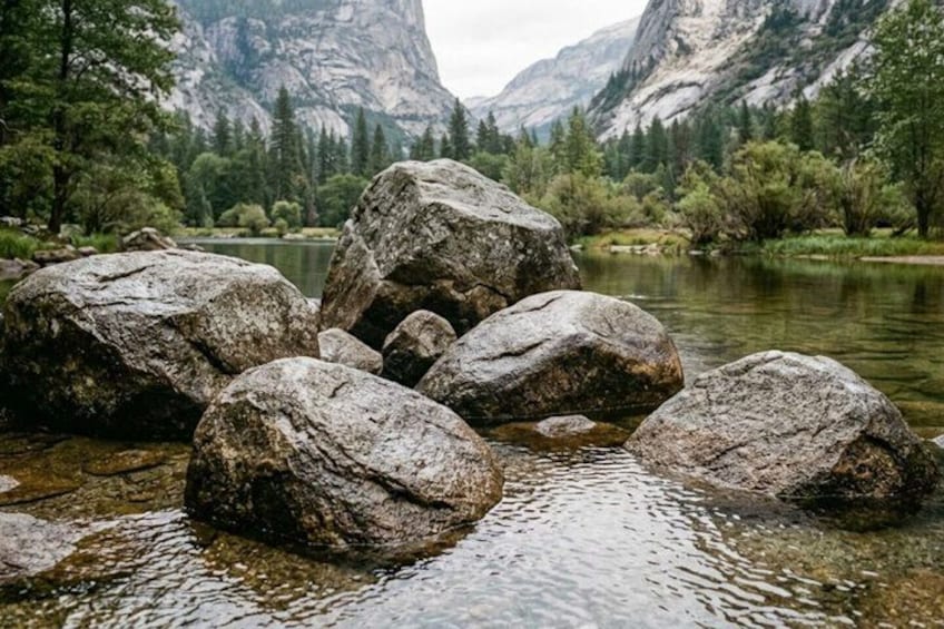 A river with large rocks in the foreground and mountains in the background. 2