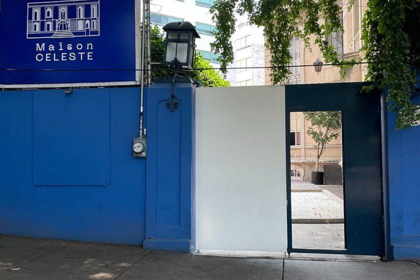 A blue building with a white door, a street lamp, and a gate. 4