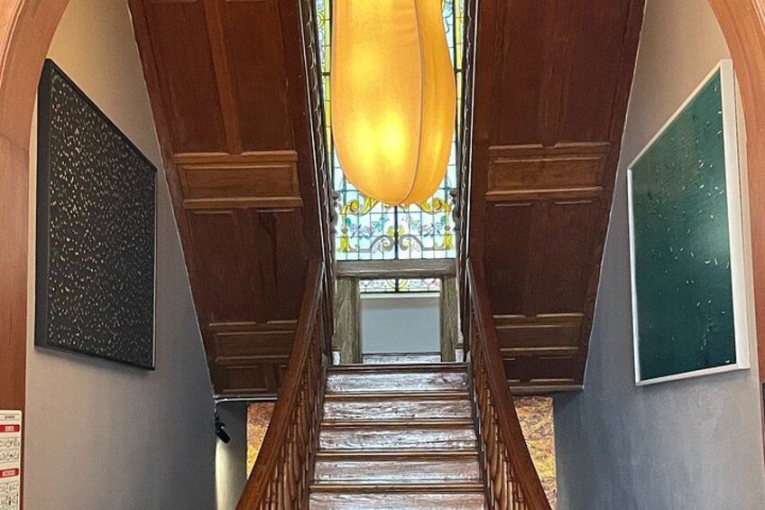 A wooden staircase with a stained glass window at the top. 5