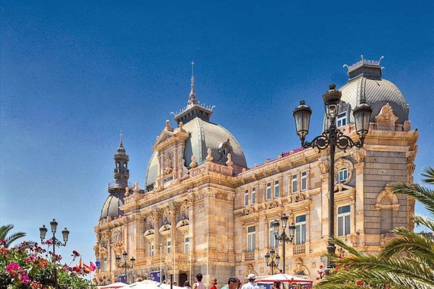 A historic building with ornate architecture, domed roofs, and a clear blue sky. 4