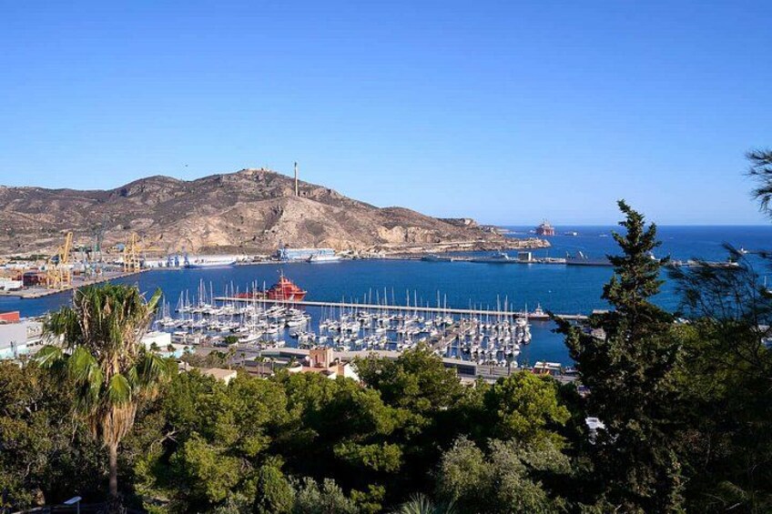 A coastal marina with boats, a crane, and a mountainous backdrop. 5