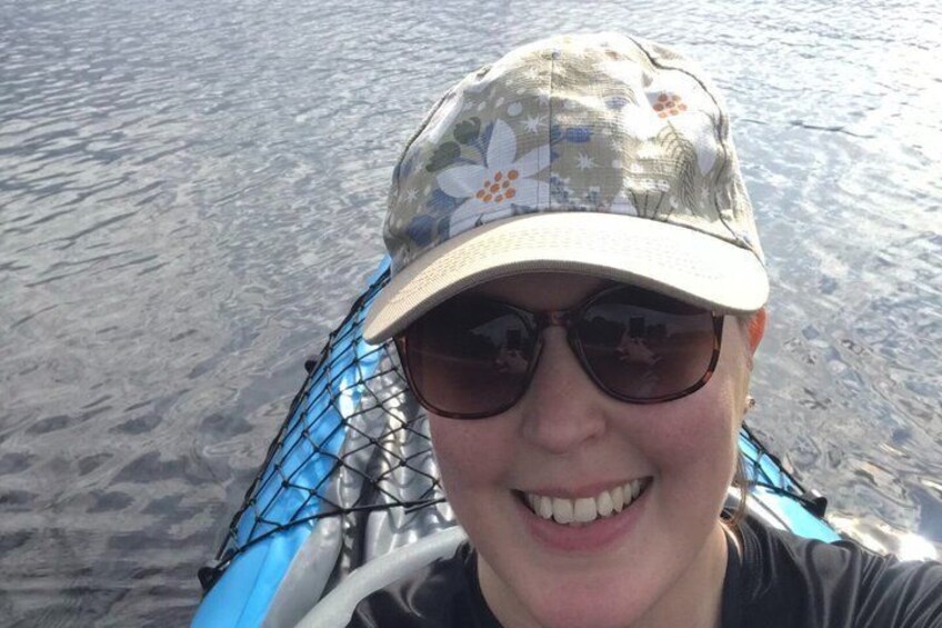 A person wearing a camouflage hat and sunglasses, seated on a boat with a blue net. 2