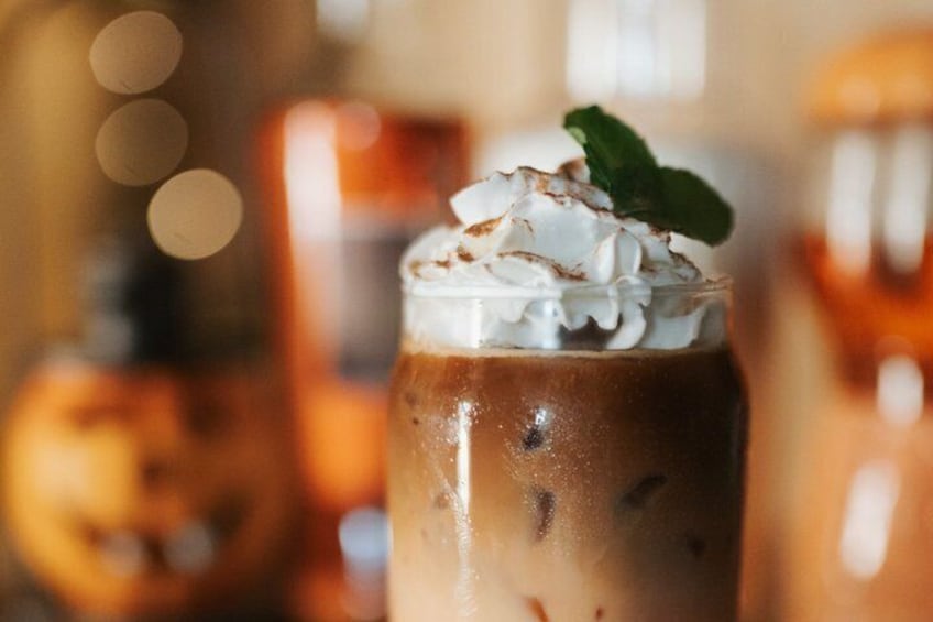 A close-up of a beverage with whipped cream and a mint garnish. 5