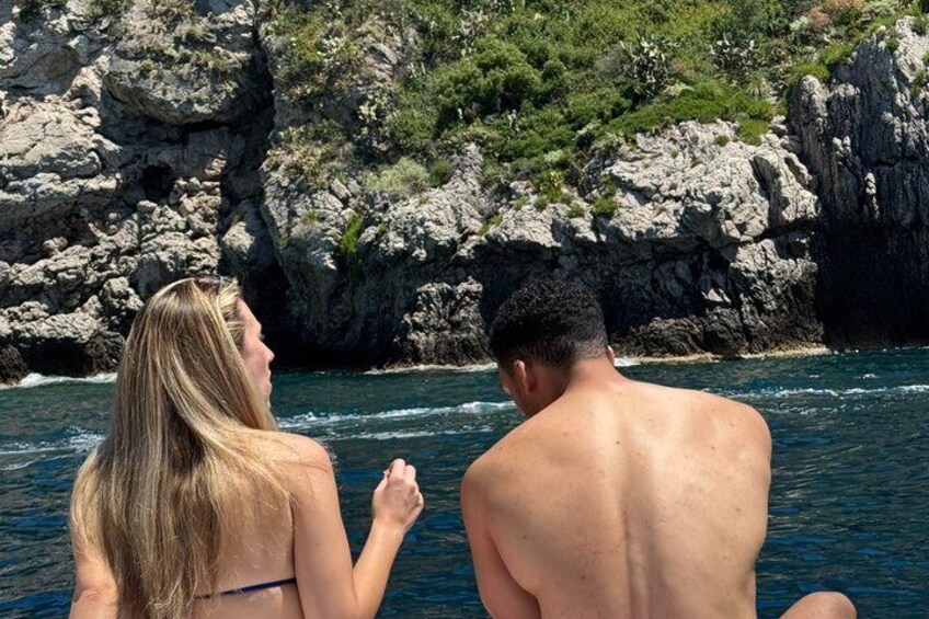 Two people on a boat near rocky cliffs. 2