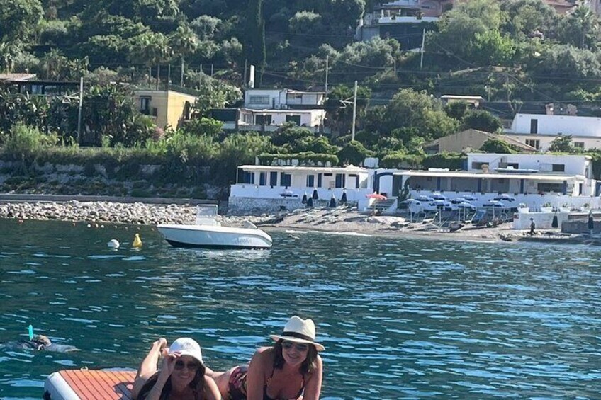 A boat on calm water, a beach with umbrellas, and buildings in the background. 5