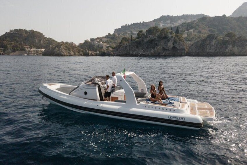 A motorboat on calm water with a rocky coastline in the background. 1