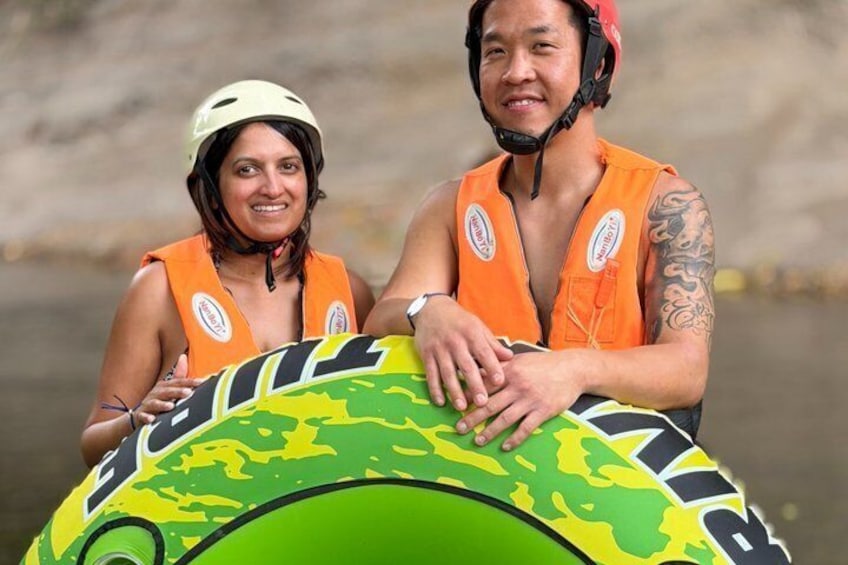 Two people holding a green inflatable raft with a map design. 3