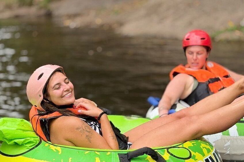 Two people in a kayak on a river, wearing helmets and life jackets. 1