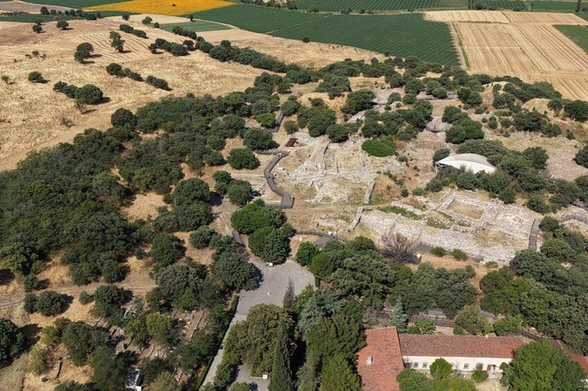 An aerial view of an archaeological site with ruins, pathways, and surrounding greenery. 2
