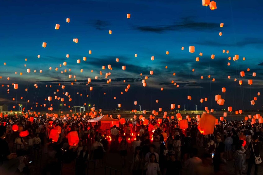 A nighttime scene with numerous people releasing sky lanterns. 3