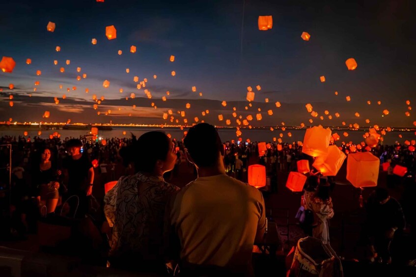 A crowd at a waterfront event releasing sky lanterns. 1