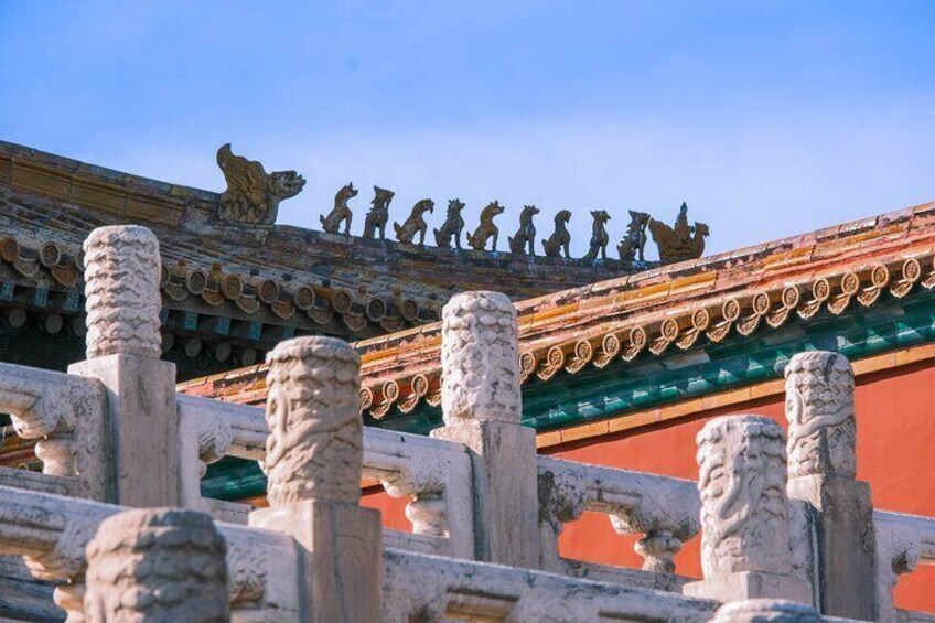 A traditional Chinese roof with lion statues and a red wall. 4