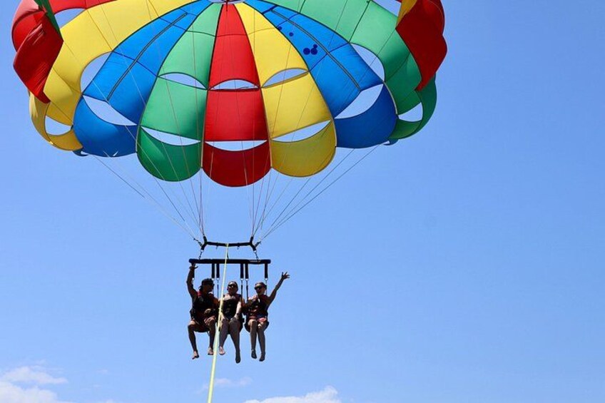 A parachute with multiple colors, a clear sky, and a person in a harness. 2