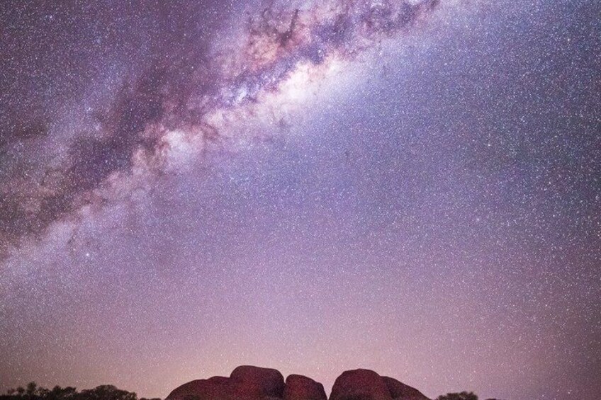 A starry night sky with the Milky Way visible, a rocky landscape, and a silhouette of a large rock formation. 3