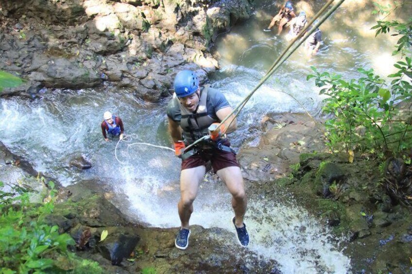 A person rappelling down a rocky waterfall. 2