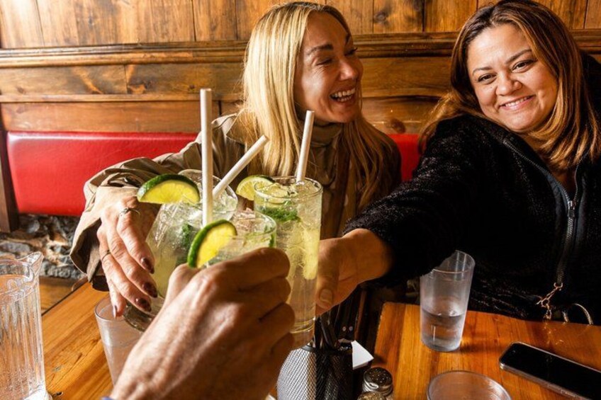 Two people sitting at a wooden table with drinks, one holding a glass with a straw. 3