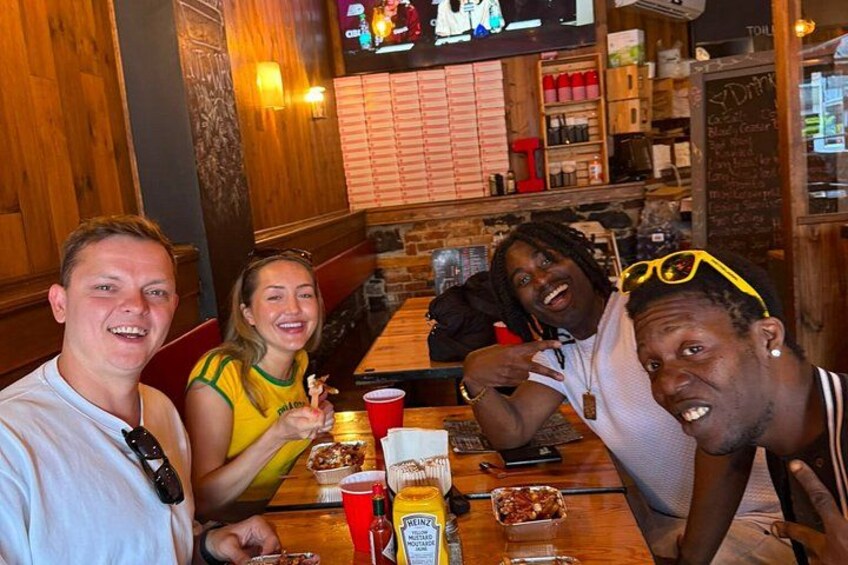 A group of people dining at a restaurant with wooden decor and a menu board in the background. 2