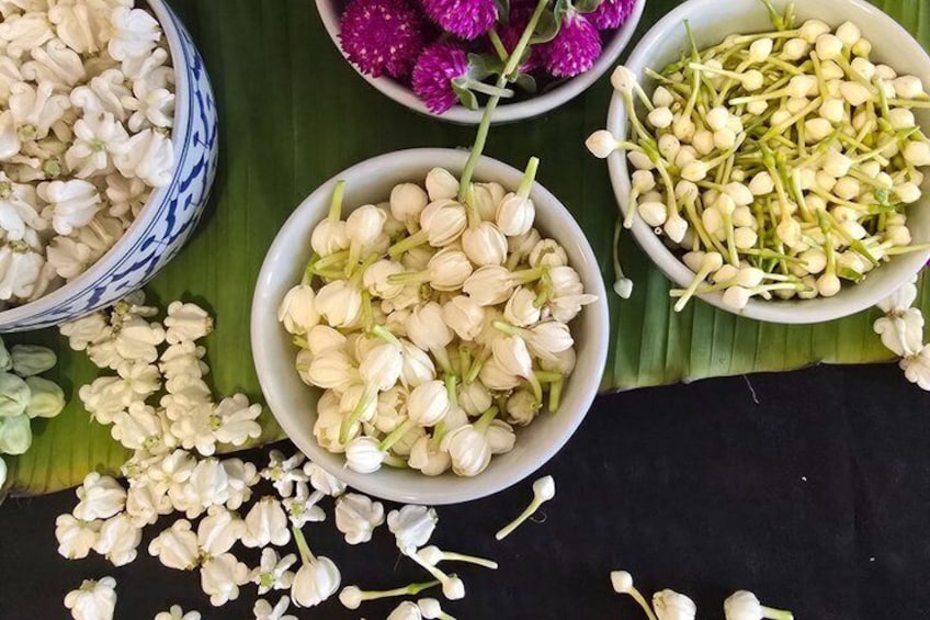 Bowls of white flowers and green buds on a black surface. 1
