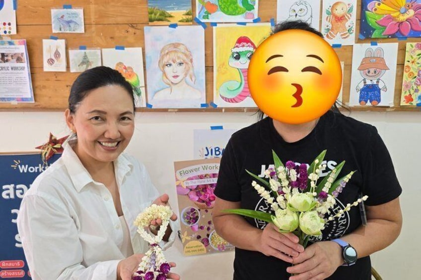 A person holding a bouquet of flowers, with a wall of children's artwork in the background. 2