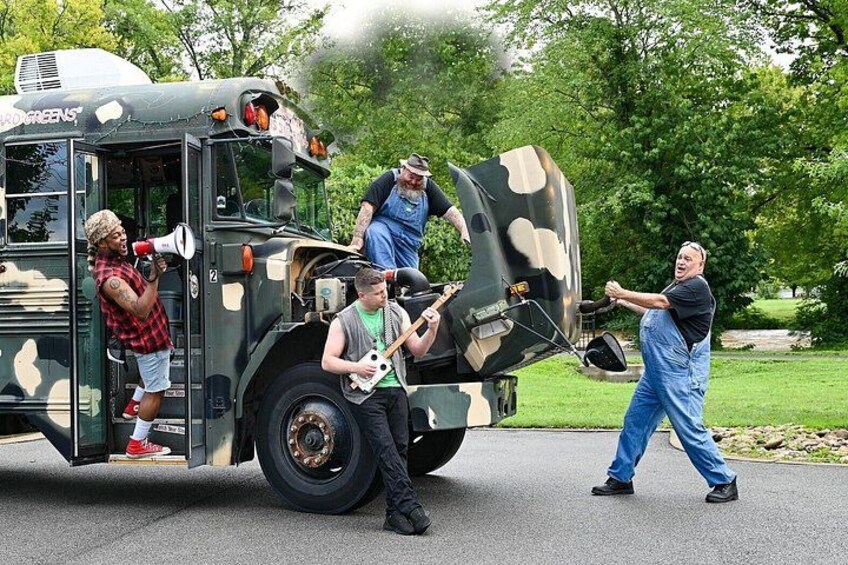 A camouflage bus with people around it, a person playing a guitar, and a person holding a megaphone. 2