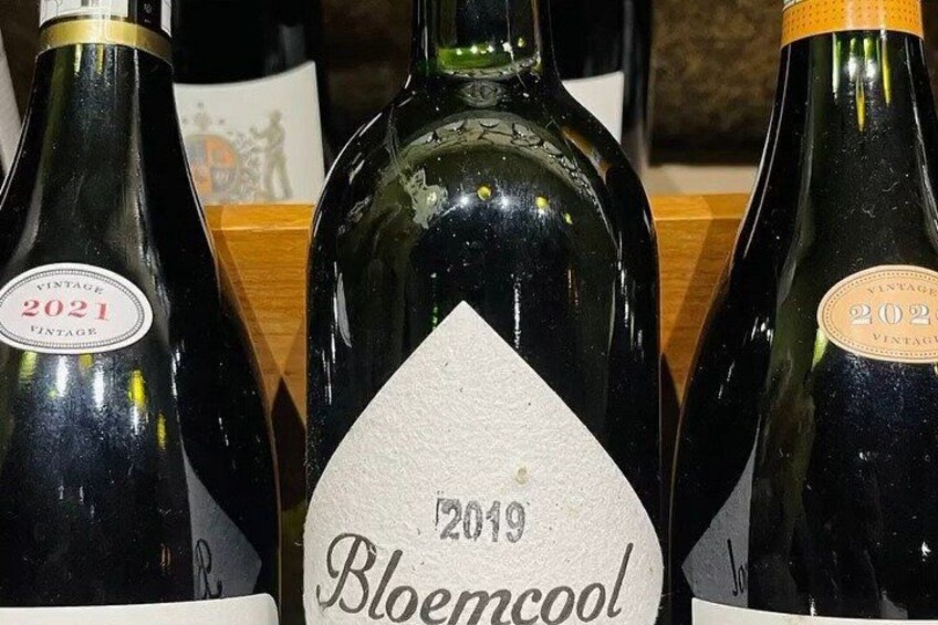 Three wine bottles with labels, one prominently displaying 'Bloemcool 2019'. 2