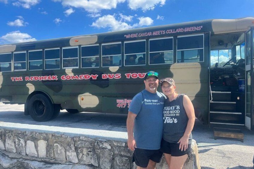 A vintage bus with 'The Redneck Comedy Bus Tour' text, parked on a stone wall. 5