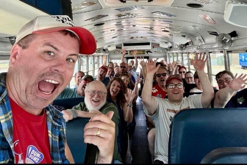 A bus interior with passengers seated and some raising their hands. 2