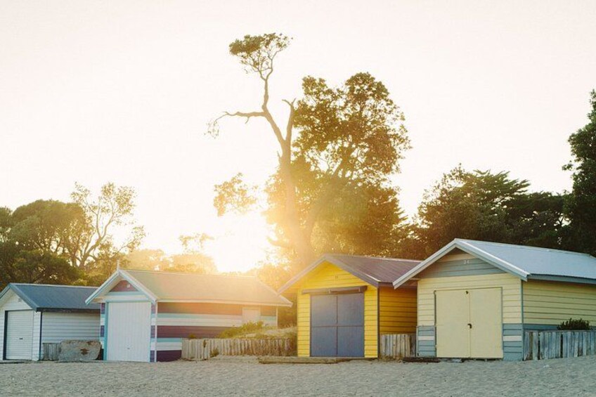 A row of beachside beach huts with a sunset in the background. 3