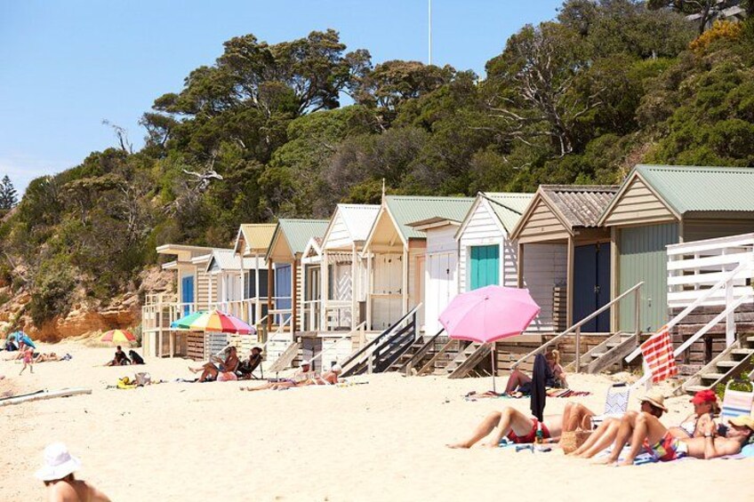 Beach huts, umbrellas, and people relaxing on the sand. 2