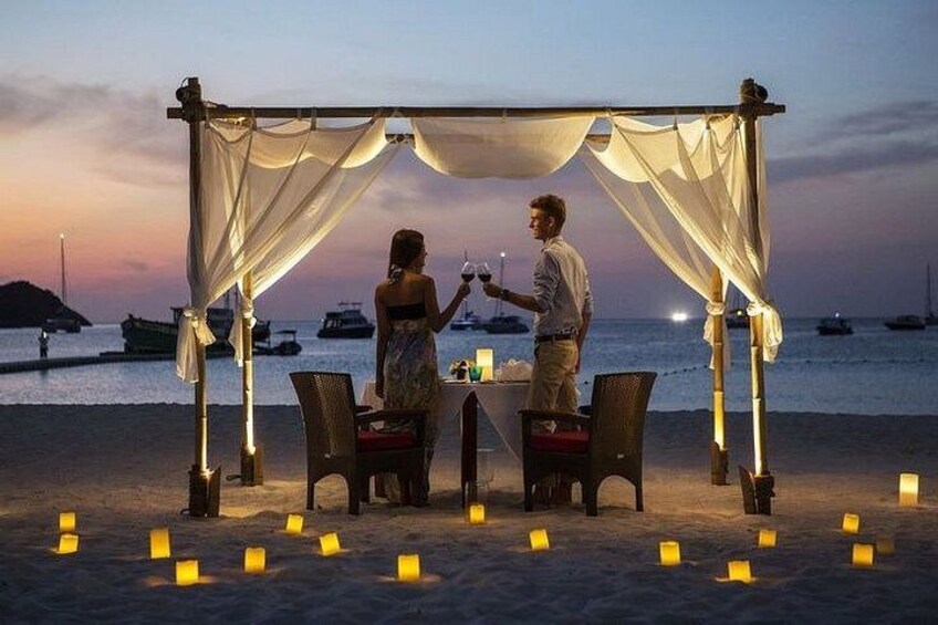 A romantic outdoor dinner setup with a canopy, candles, and a view of the sea at dusk. 5
