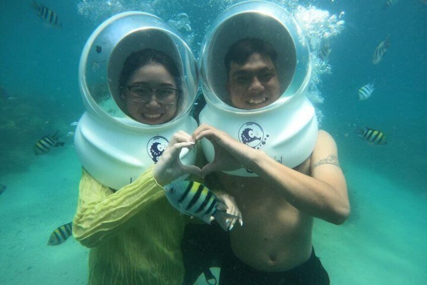 Two people underwater wearing scuba gear, surrounded by fish. 4